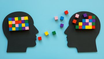 Zwei Menschen sprechen miteinander, grafisch umgesetzt mit schwarzem Papier für die Köpfe und bunten Bausteinen für die Wörter.